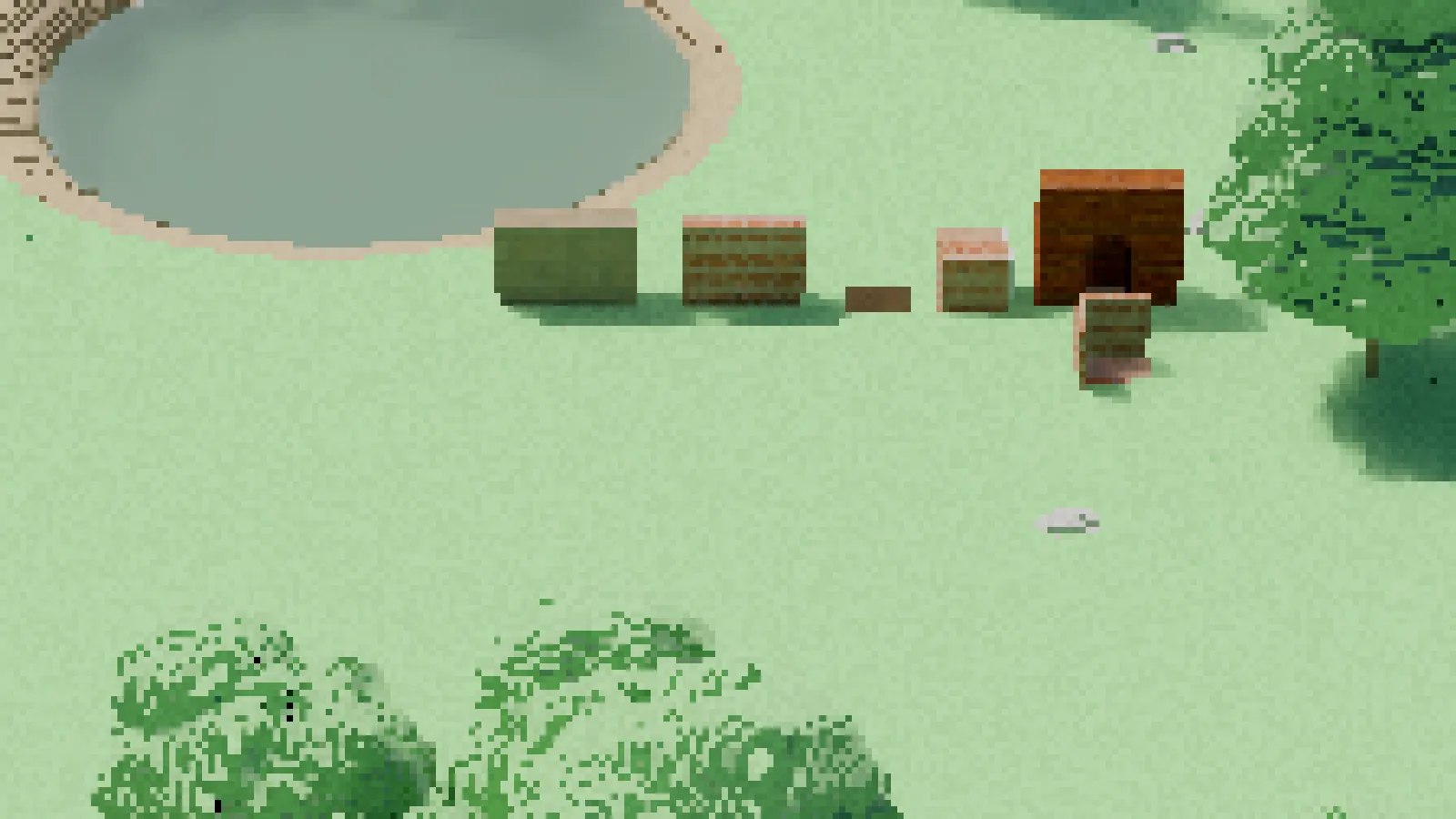A zoomed view from about 90 metres of blocks built in the meadow: the doorway reads closed, a carved-away block still stands and the floors are missing.
