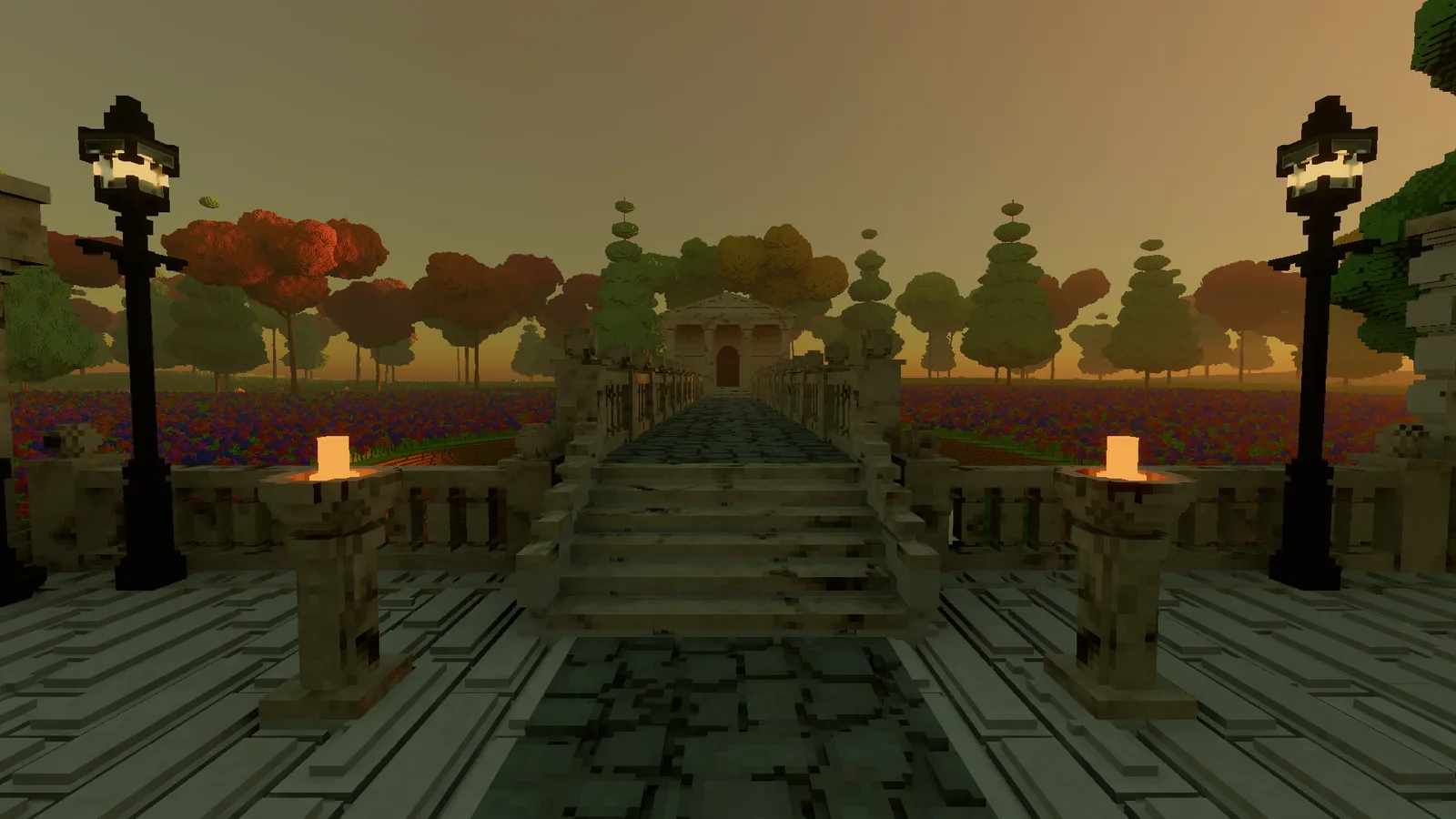 The courtyard at dusk, looking toward the stairs up to the bridge, with orange fire bowls on either side and warm street lamps against an orange sky.