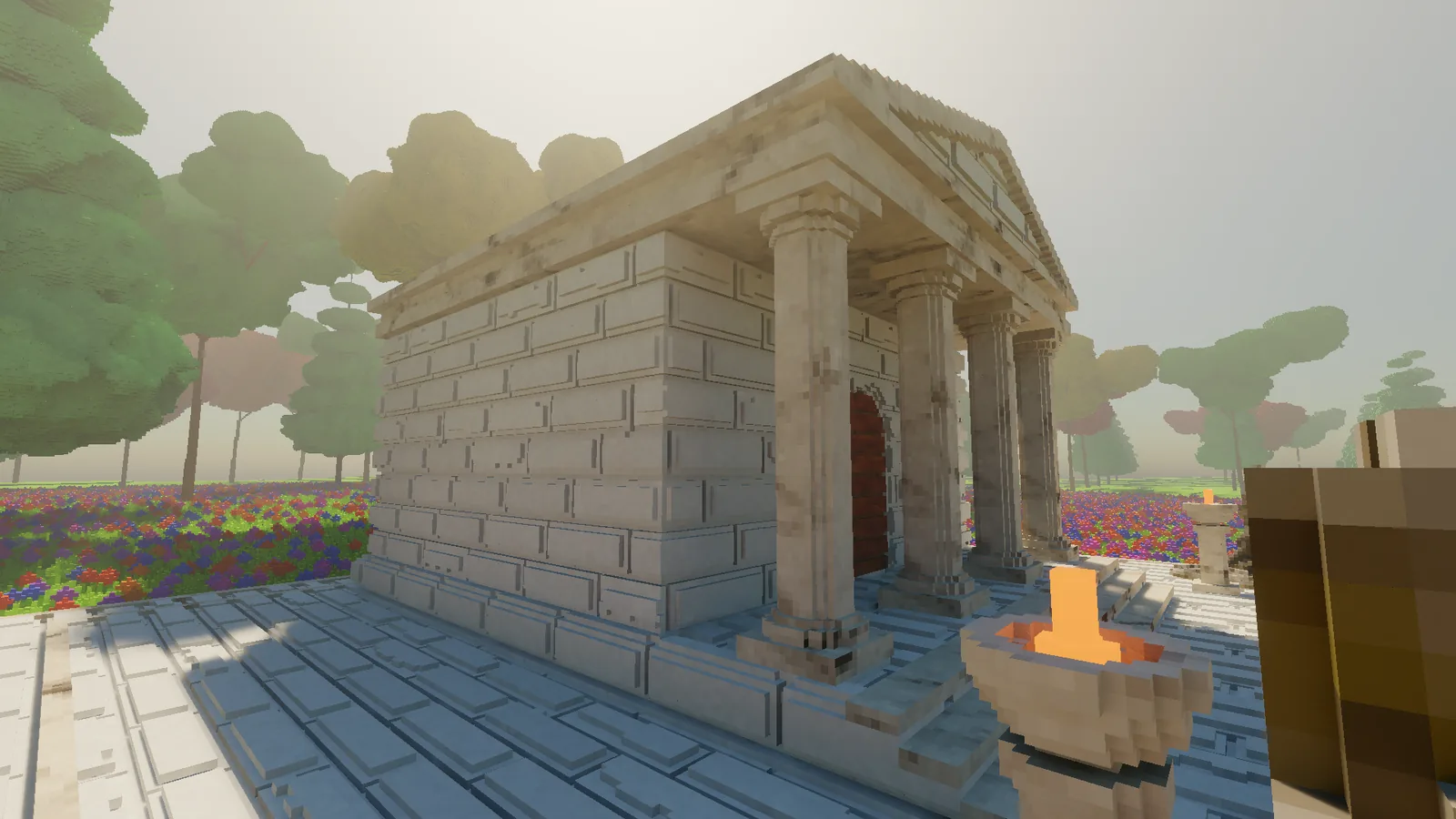 The temple on its terrace, a white stone building with a columned portico and a brick roof, with a fire bowl in the foreground.