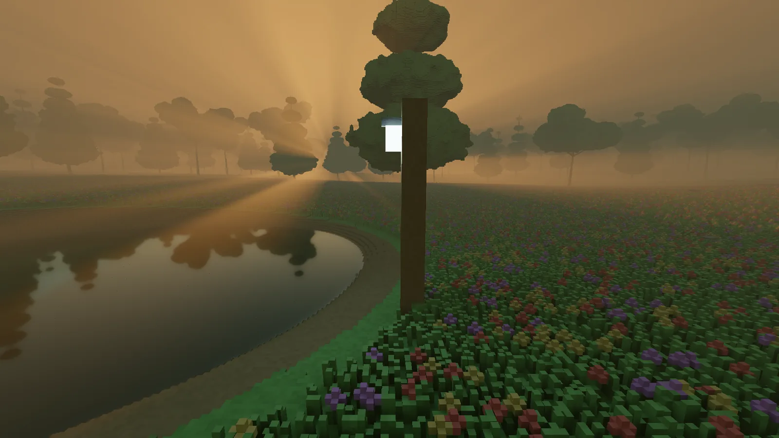 A lantern on a post beside the pond at dusk, sun shafts fanning through the haze behind the treeline and the glow mirrored in the water.