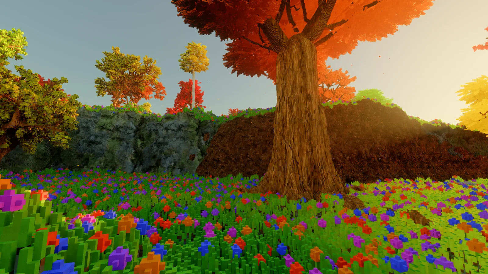 A wall of grey rock and dark earth rising behind a flower meadow, with a large red-crowned tree standing on top of it.